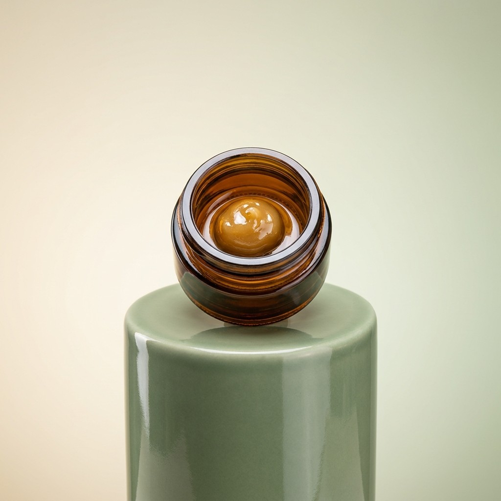 Amber jar of cannabis rosin on a sage ceramic podium
